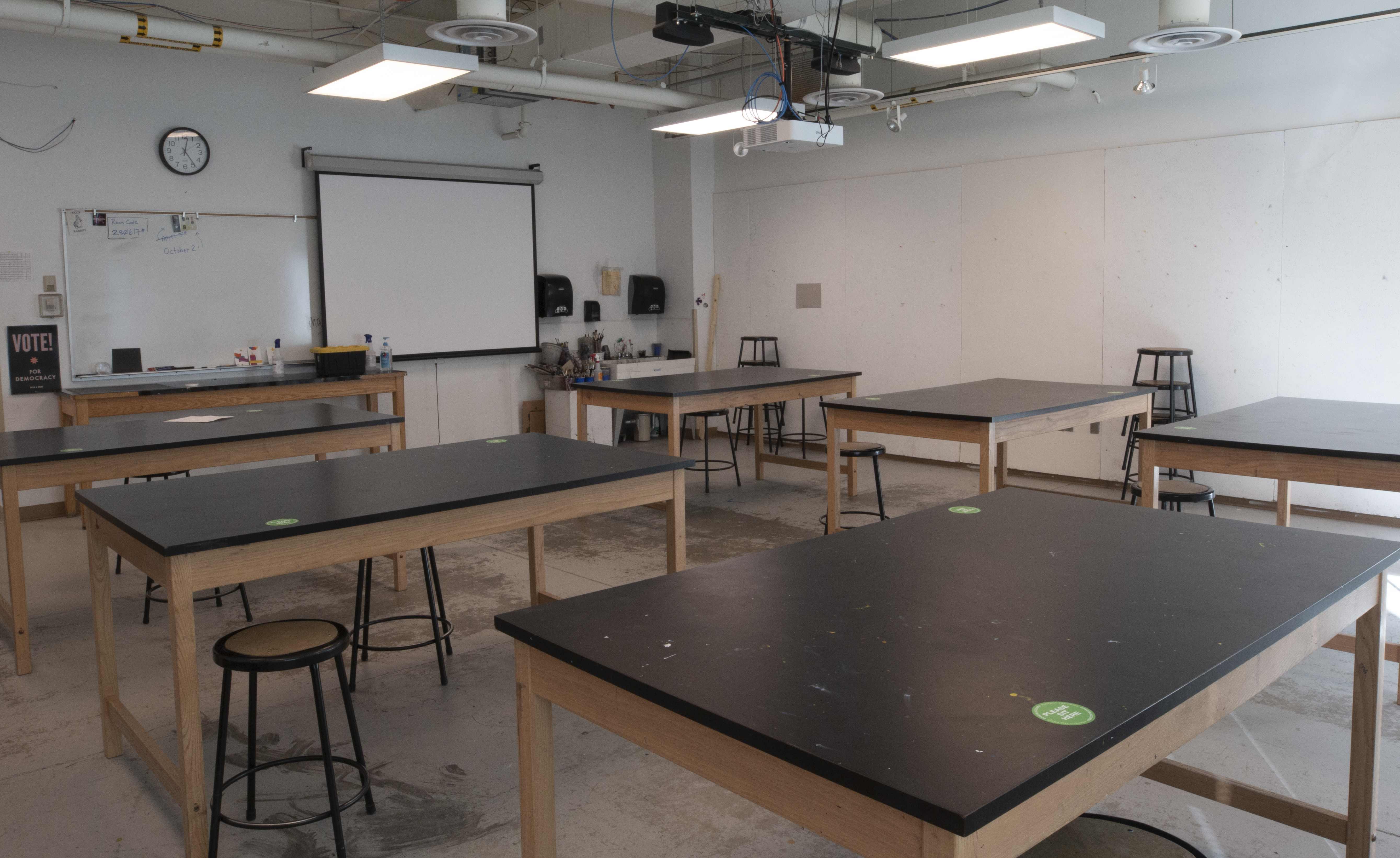 Classroom with projector, screen, and flat desks for drawing