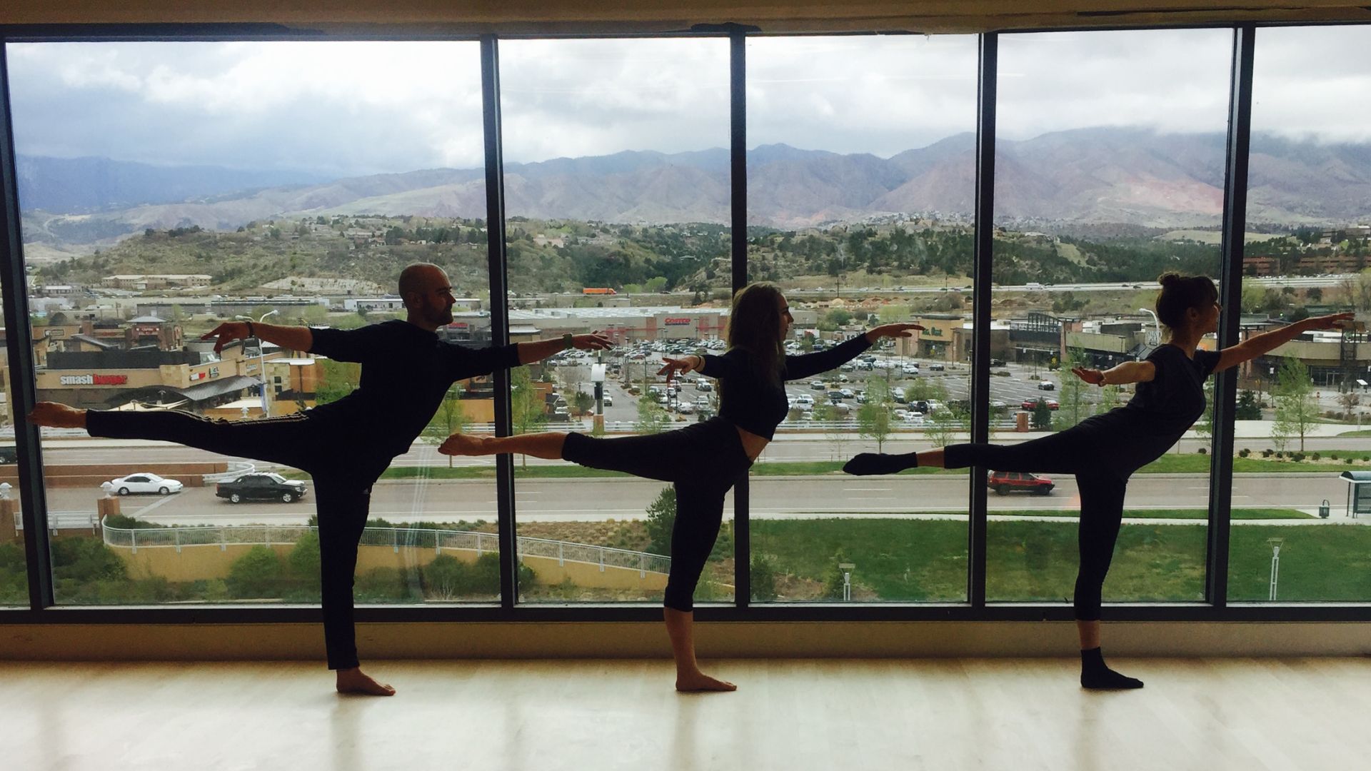 three people dancing in studio with large windows overlooking Front Range