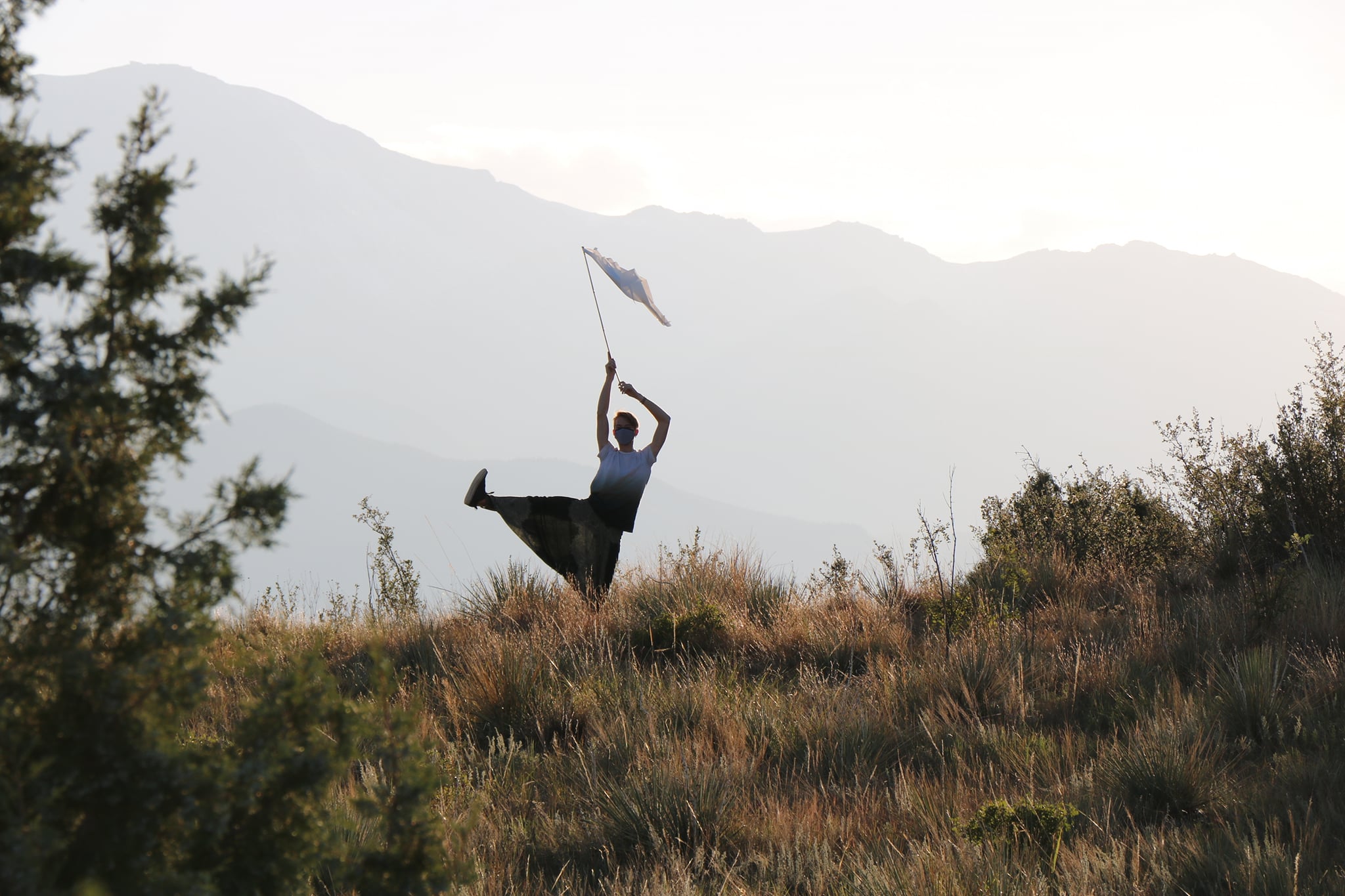 Dohee Lee dancing in field with flag and mountain backdrop