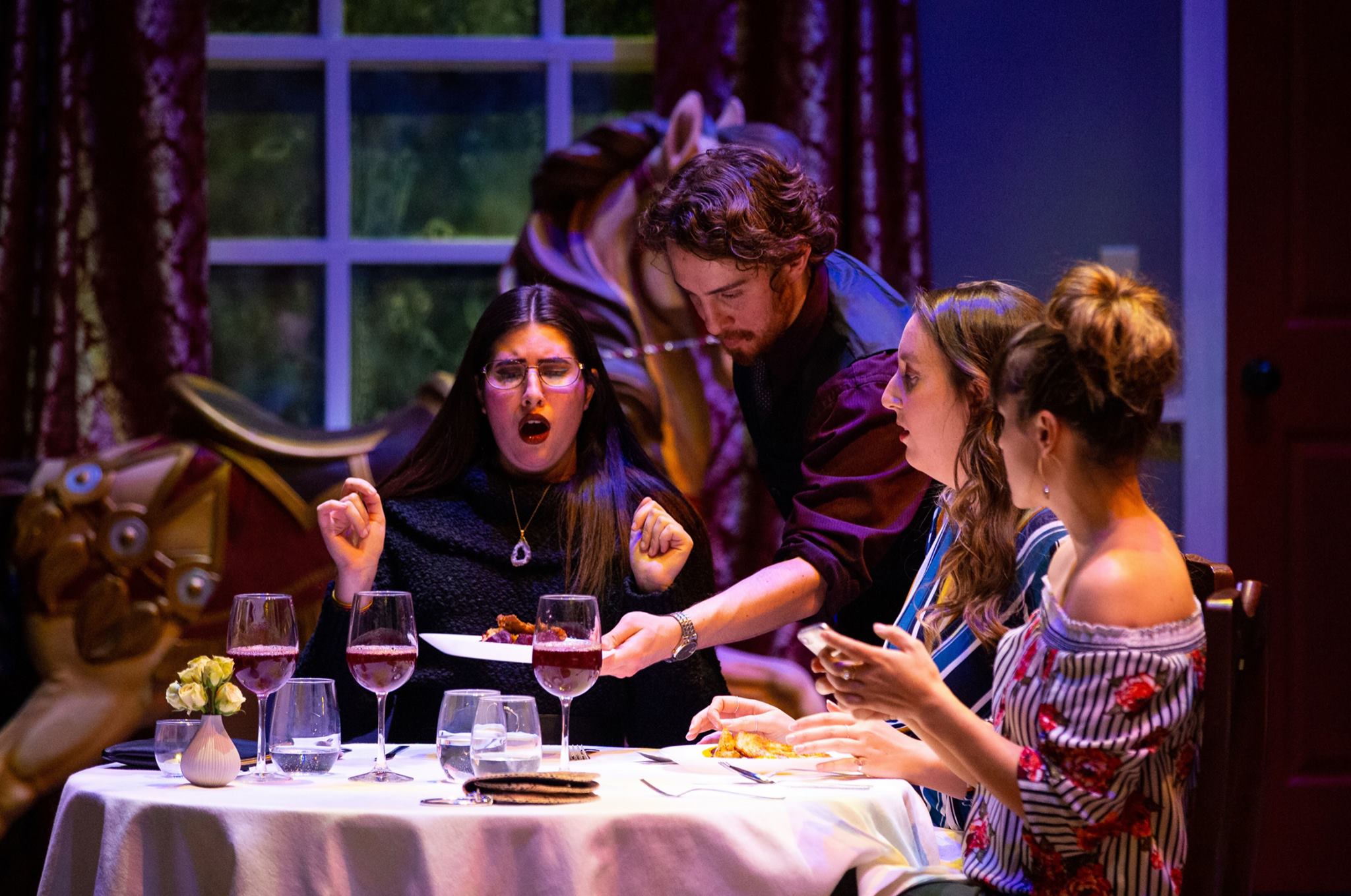 people at a table with wine in glasses and one person standing