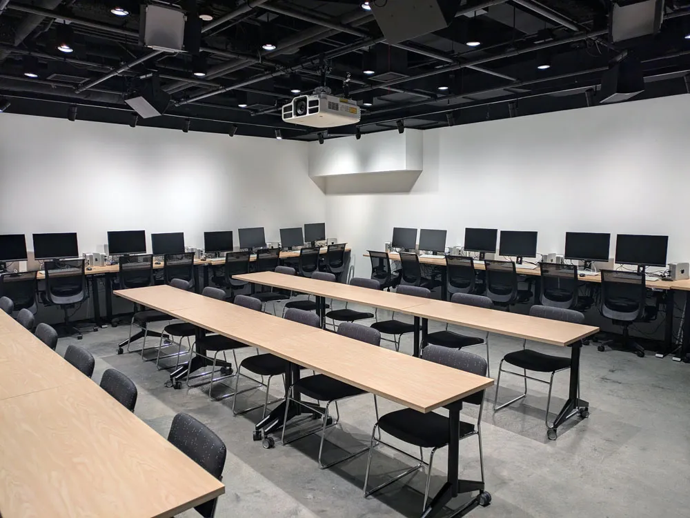 Three desks with chairs and computers lining the walls